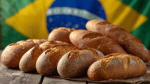 Pães artesanais sobre mesa de madeira com bandeira do Brasil ao fundo