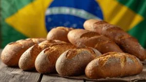 Pães artesanais sobre mesa de madeira com bandeira do Brasil ao fundo